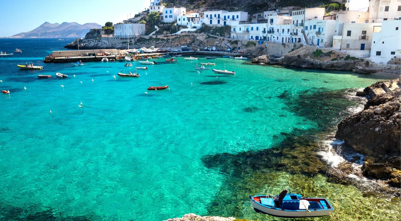 Boats moored in the turquoise harbour of Cala Dogana below Levanzo village