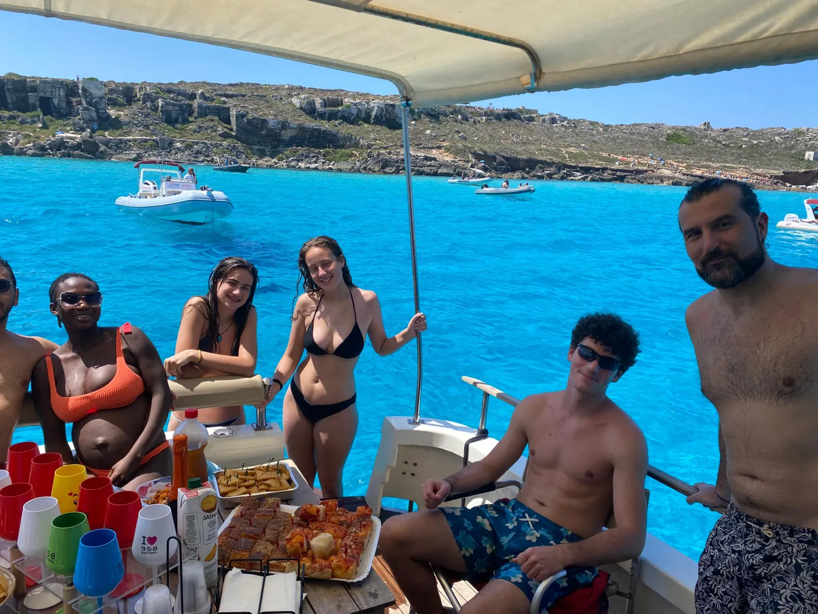 Guests eating lunch under the boat's awning at a swim stop