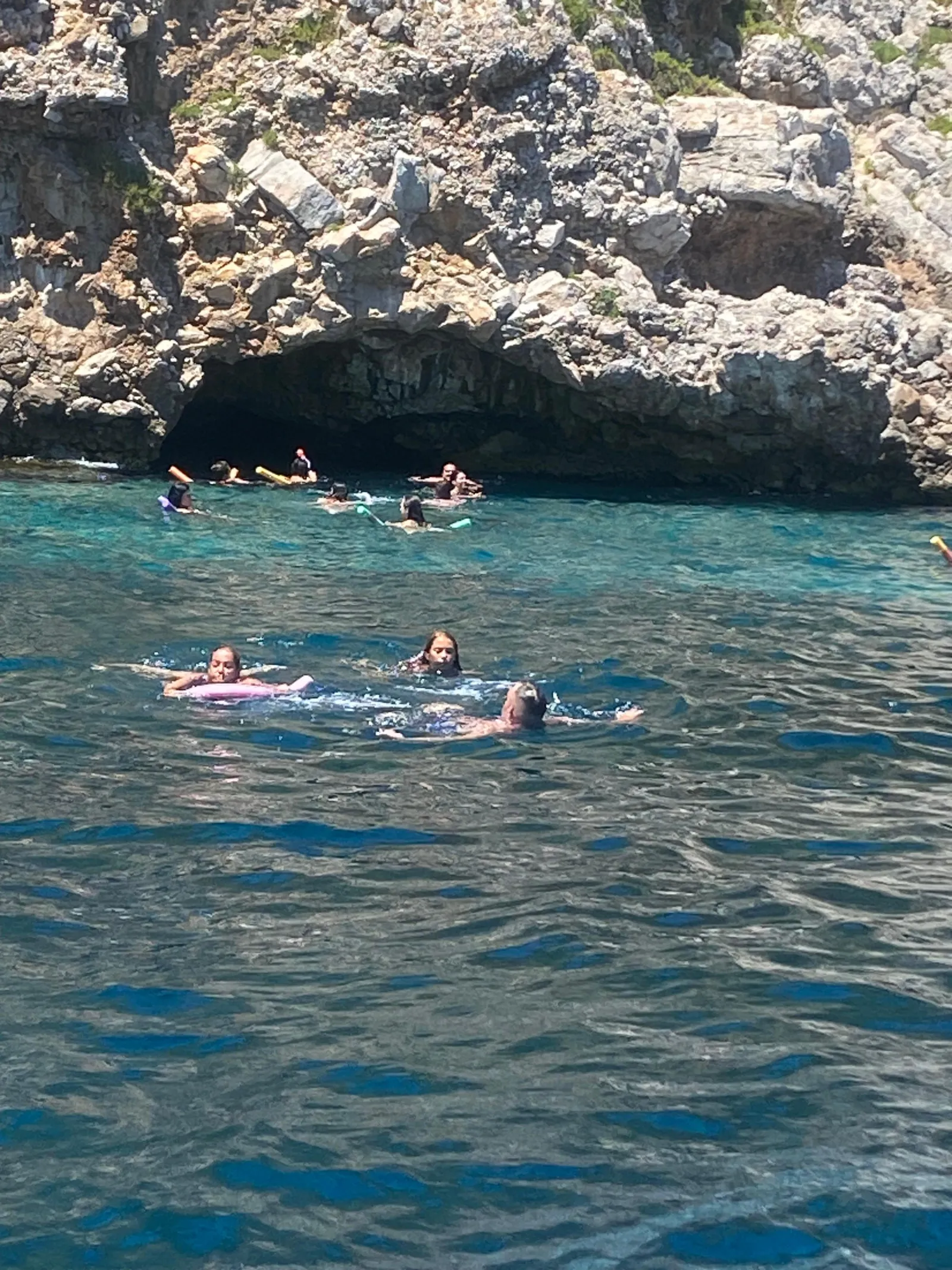 Swimmers in the water beside the rocks at one of the coves