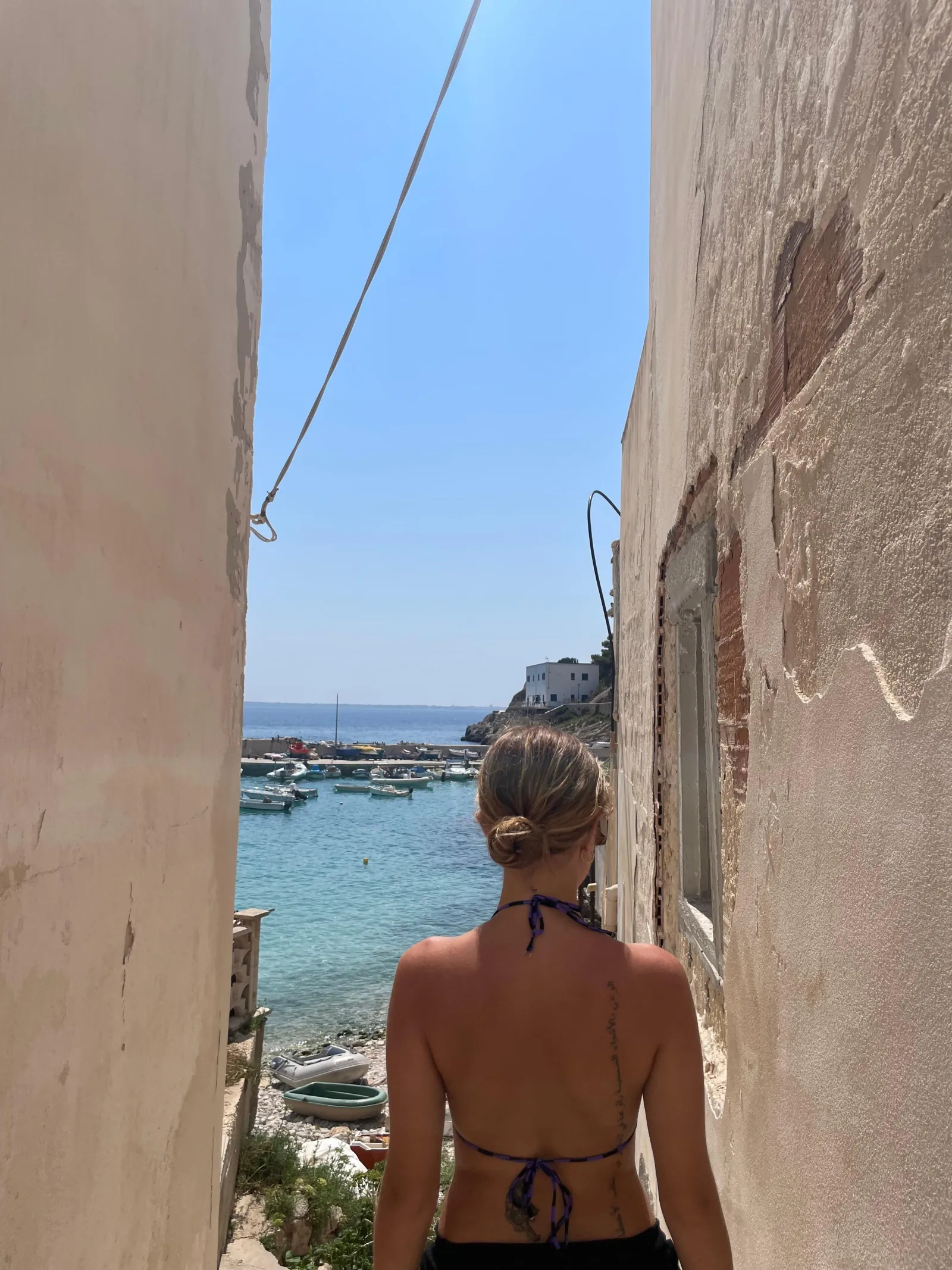 A guest looking out to the sea through a gap between village buildings