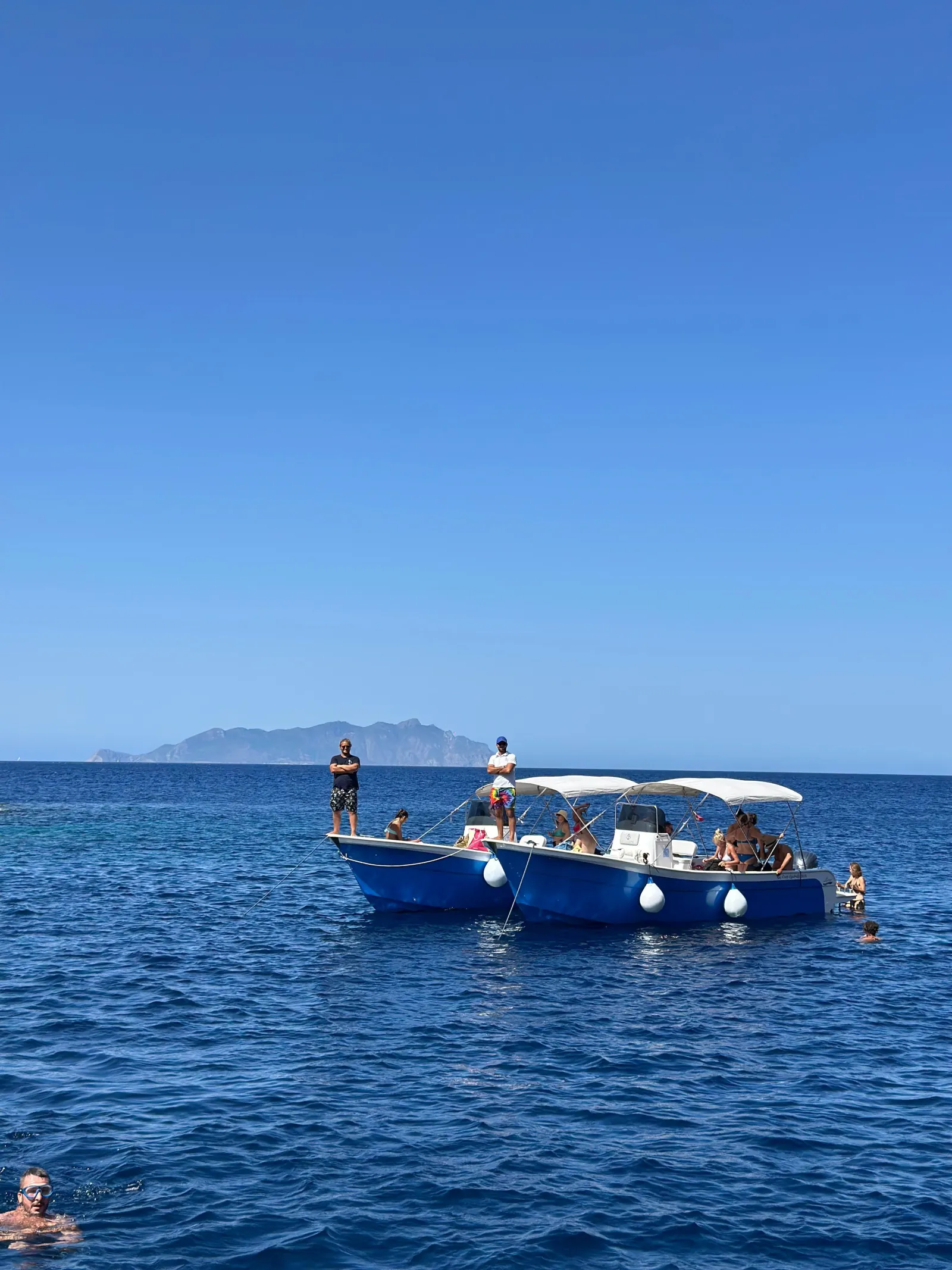 The boat on deep blue water with the mainland coast on the horizon