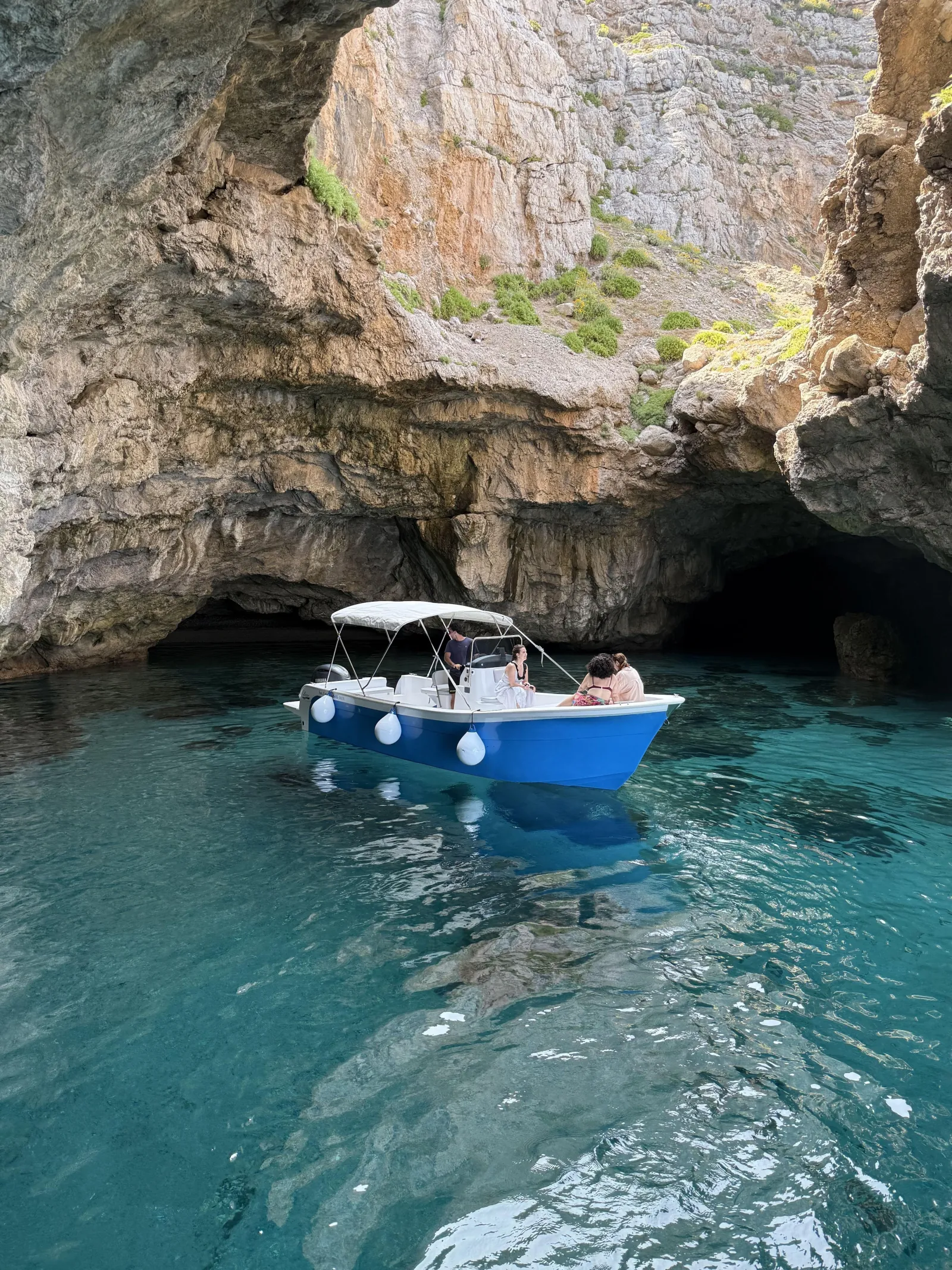 The boat moored inside a shaded sea cave on the island coast