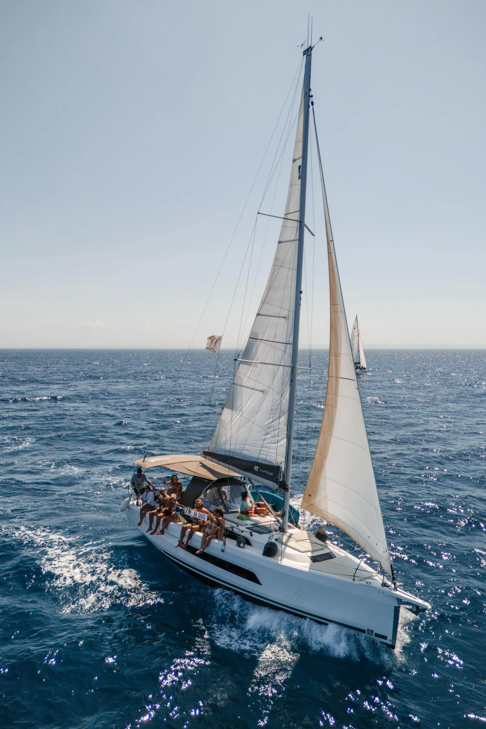 The sailing yacht under full canvas with guests out on the foredeck