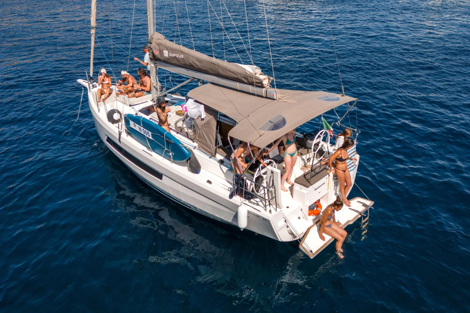 Guests spread across the deck of the sailing yacht at anchor
