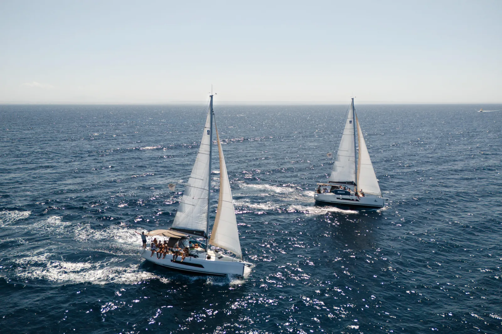 The yacht under sail alongside a second boat on a breezy afternoon