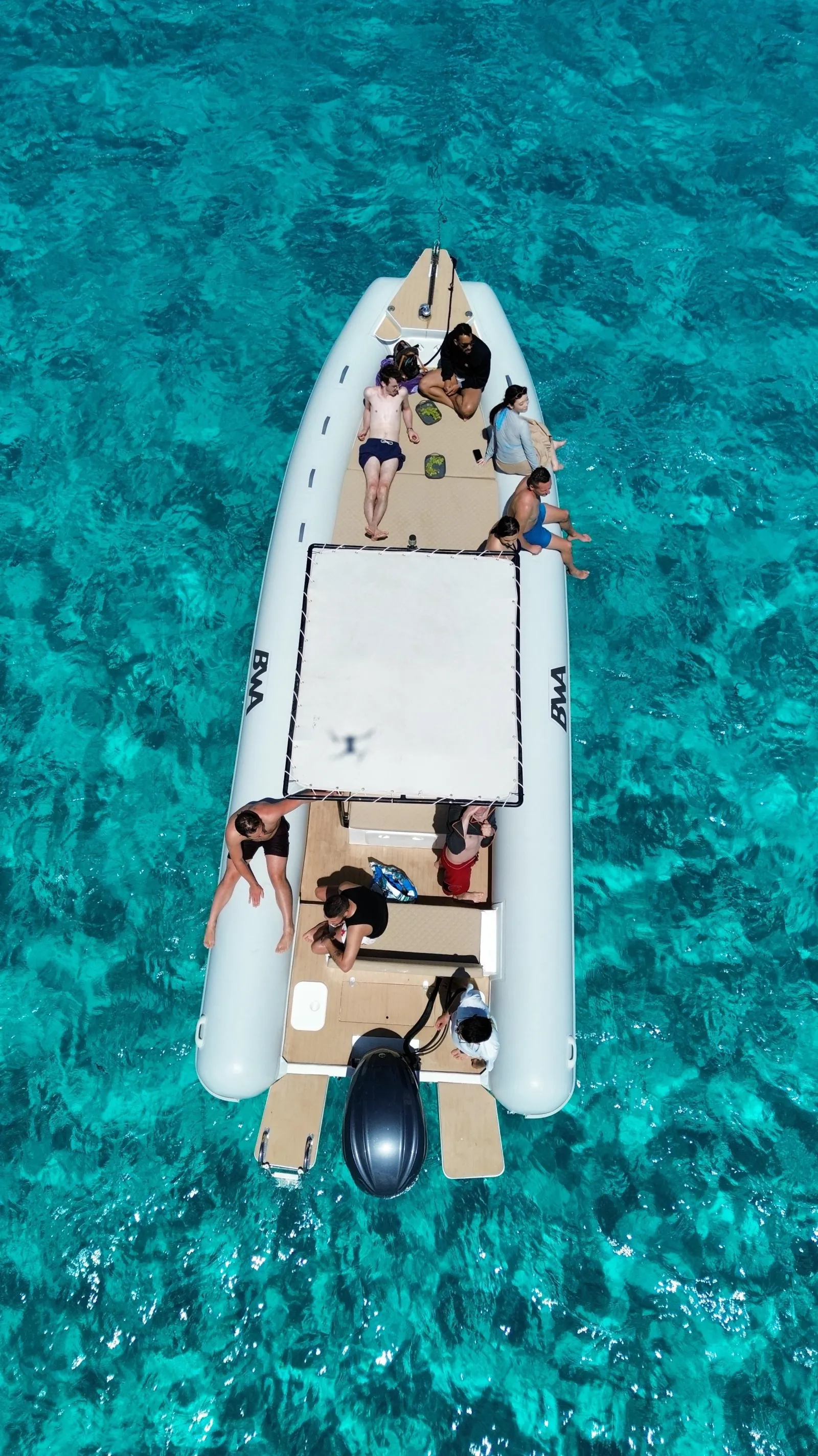 The boat's inflatable swim platform deployed at anchor, guests resting on it in the water