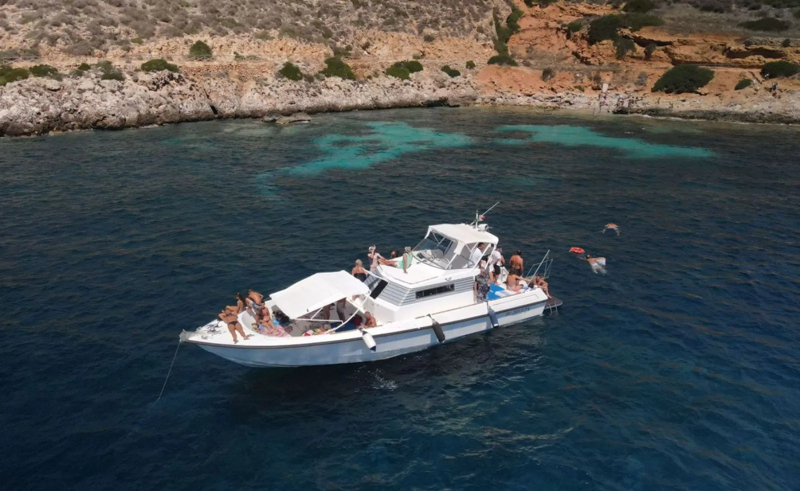 Guests aboard the yacht cruising below the Favignana cliffs