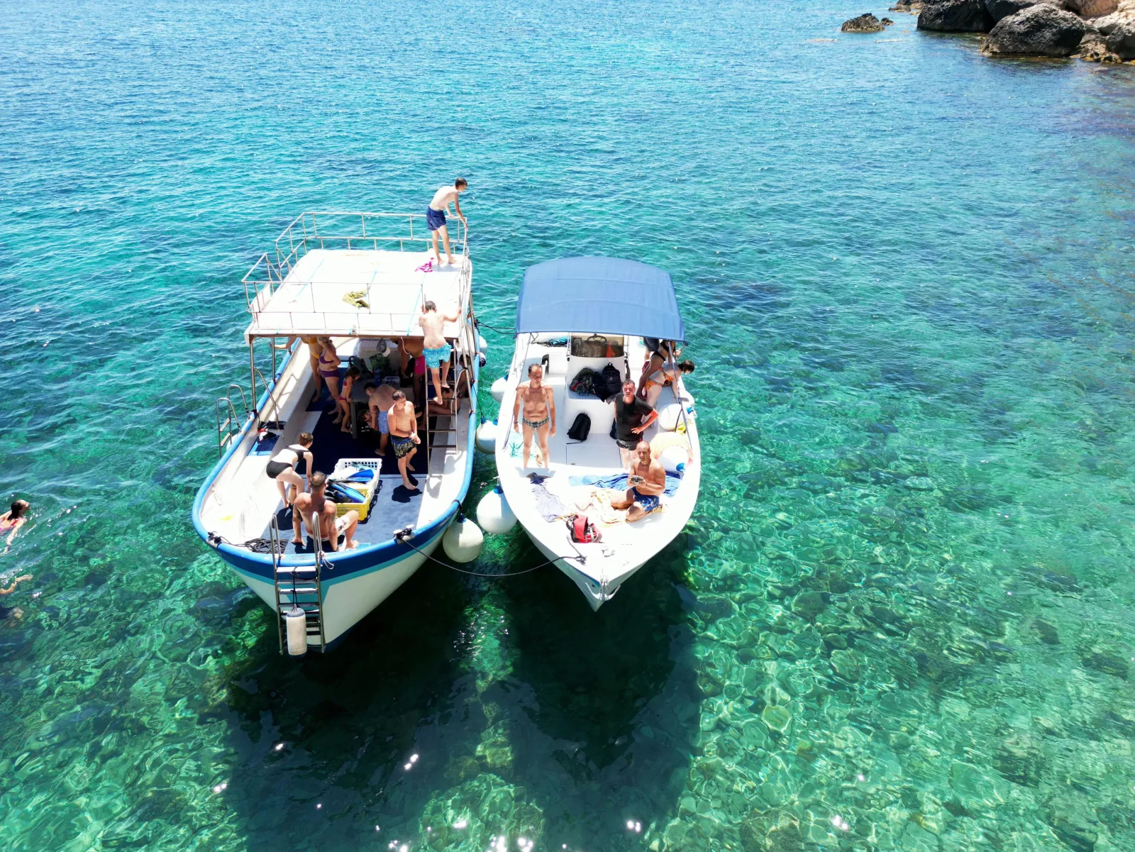 Two of the operator's boats rafted together at a swim stop, guests in the water