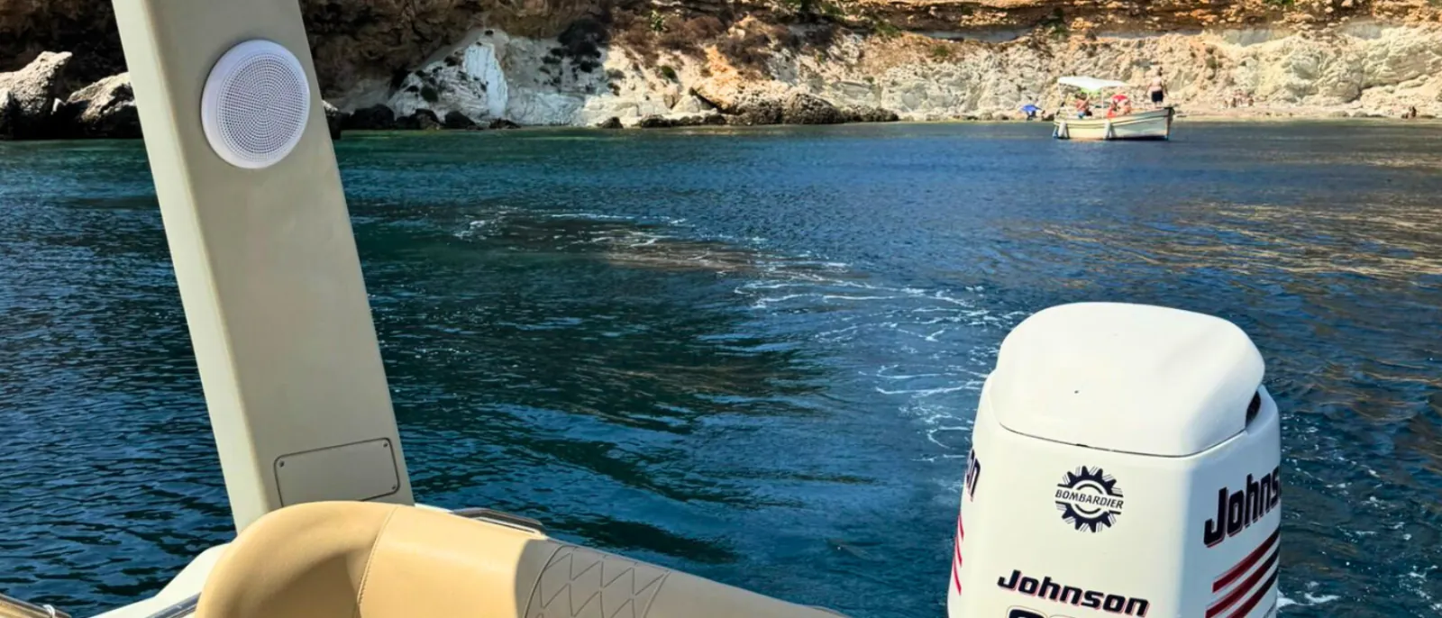 The stern and outboard alongside the rock wall of a Favignana cove
