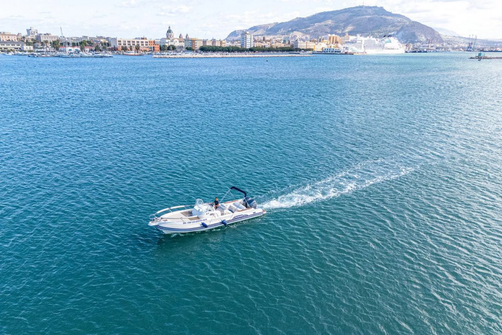 The dinghy running out of Trapani with the town and Monte Erice behind